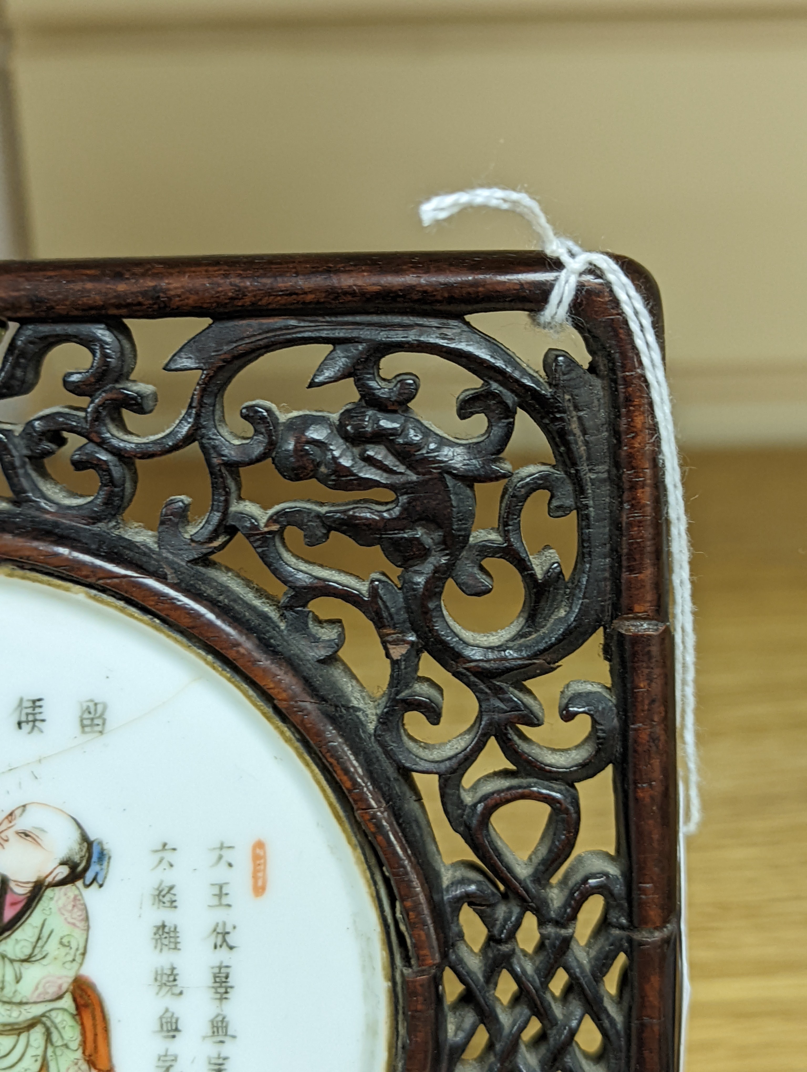 A 19th century Chinese famille rose circular plaque or cover, inset into a wood surround, cracks 15cm sq